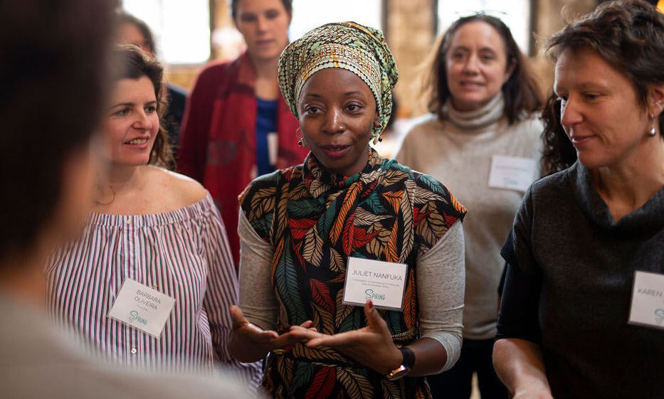 A woman faces someone while talking and standing in between two other women